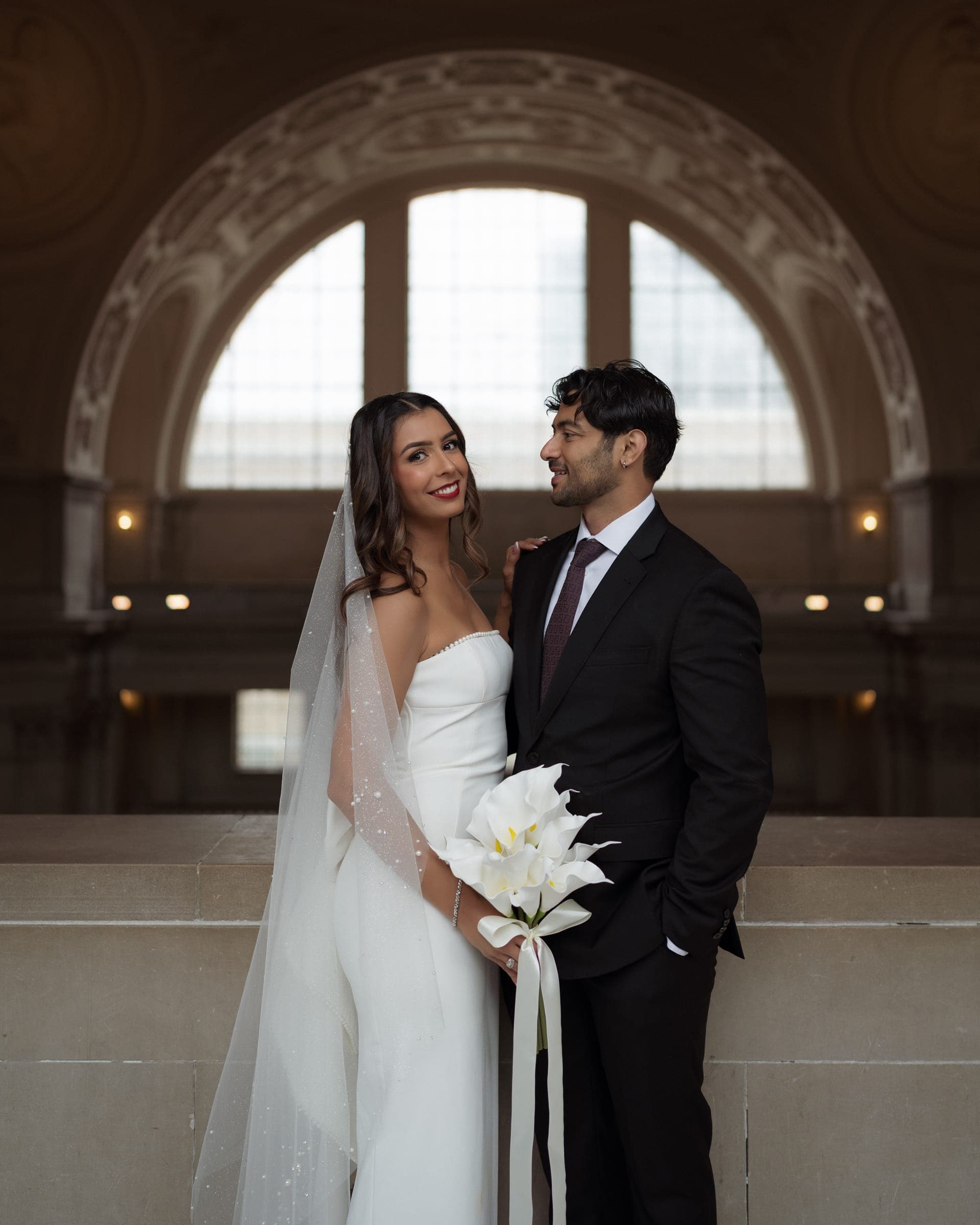 Bishal and Anna beneath an arched window at City Hall