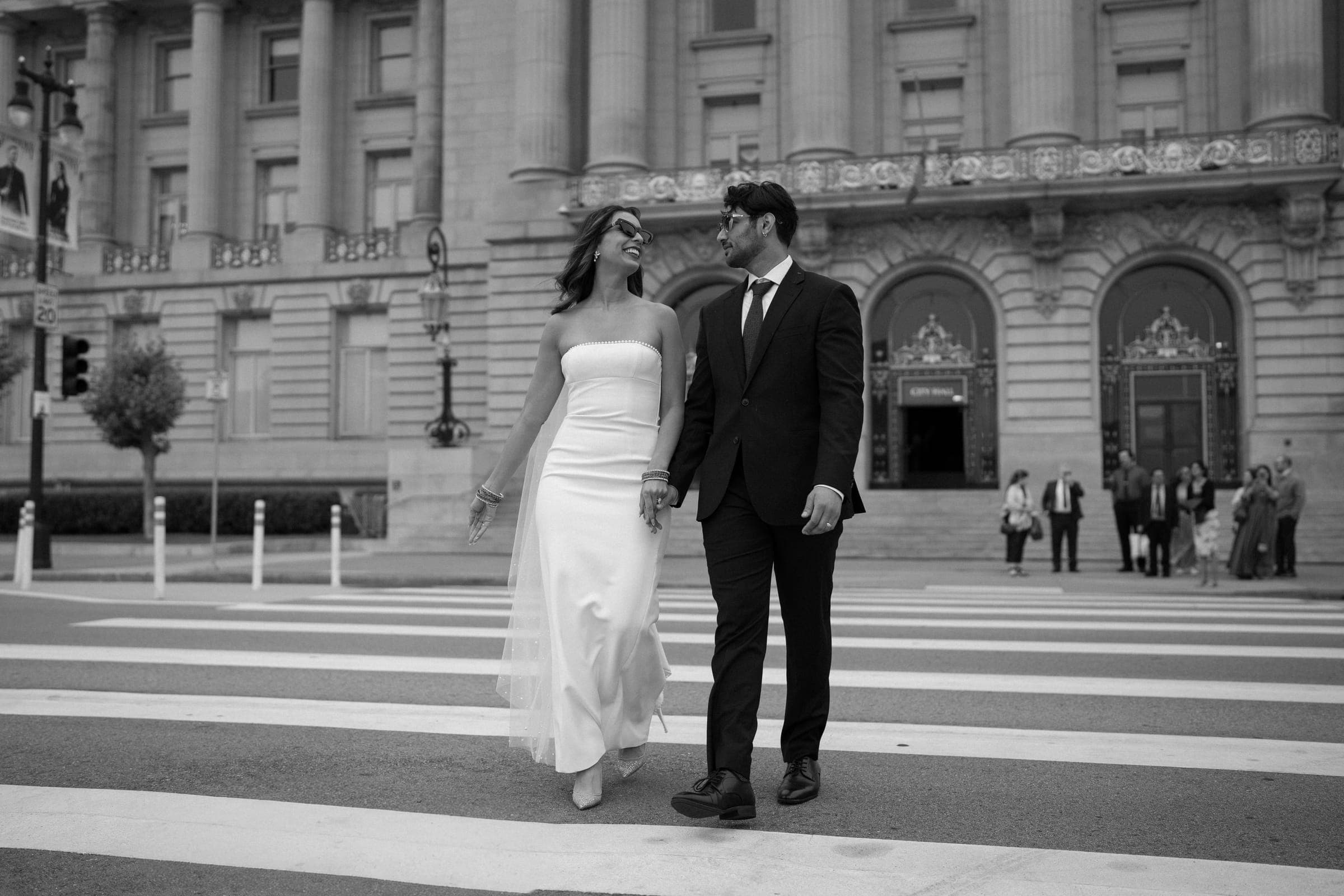 Bishal and Anna crossing the street in front of City Hall, in black and white